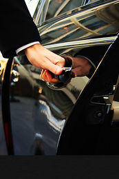 Corporate chauffeur opening luxury car door